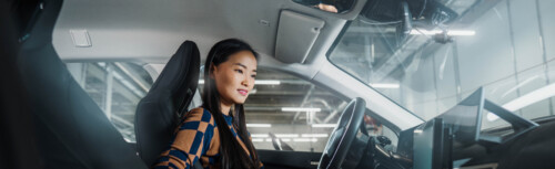 Asiatische Frau sitz in einem Auto und schaut auf ein Display.